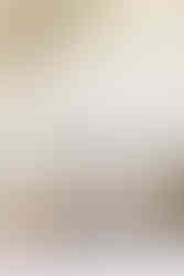 A young girl sits on a couch and makes a peace sign with both hands