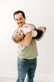 dad playing and holding son upside down