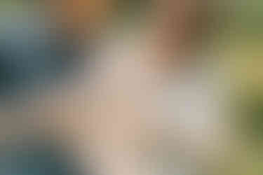 a man holds a baby who is smiling as a woman next to him holds hthe baby's hand and they look down at him