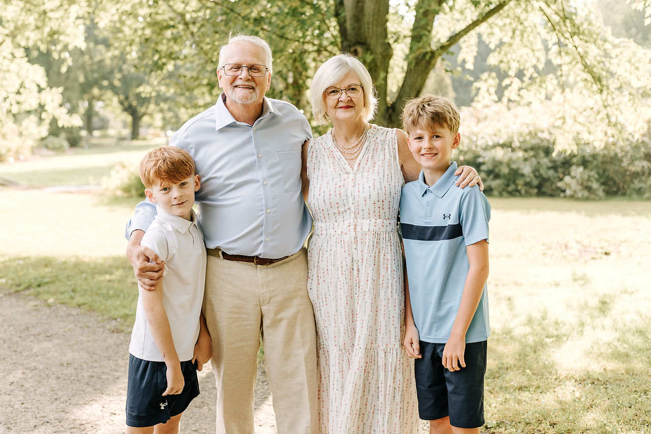 An older couple stand with their arms around two young boys