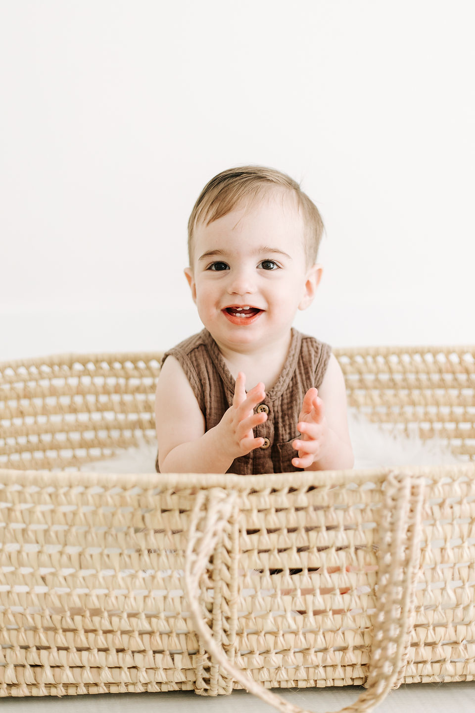 A young boy sits in a moses basket