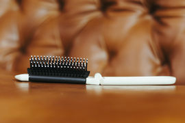 A hair brush lies on a brown couch