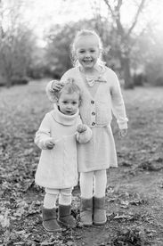 Two girls smile and hug as they stand on leaves in the fall