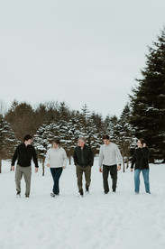 A family of five with grown children walk and talk in the snow