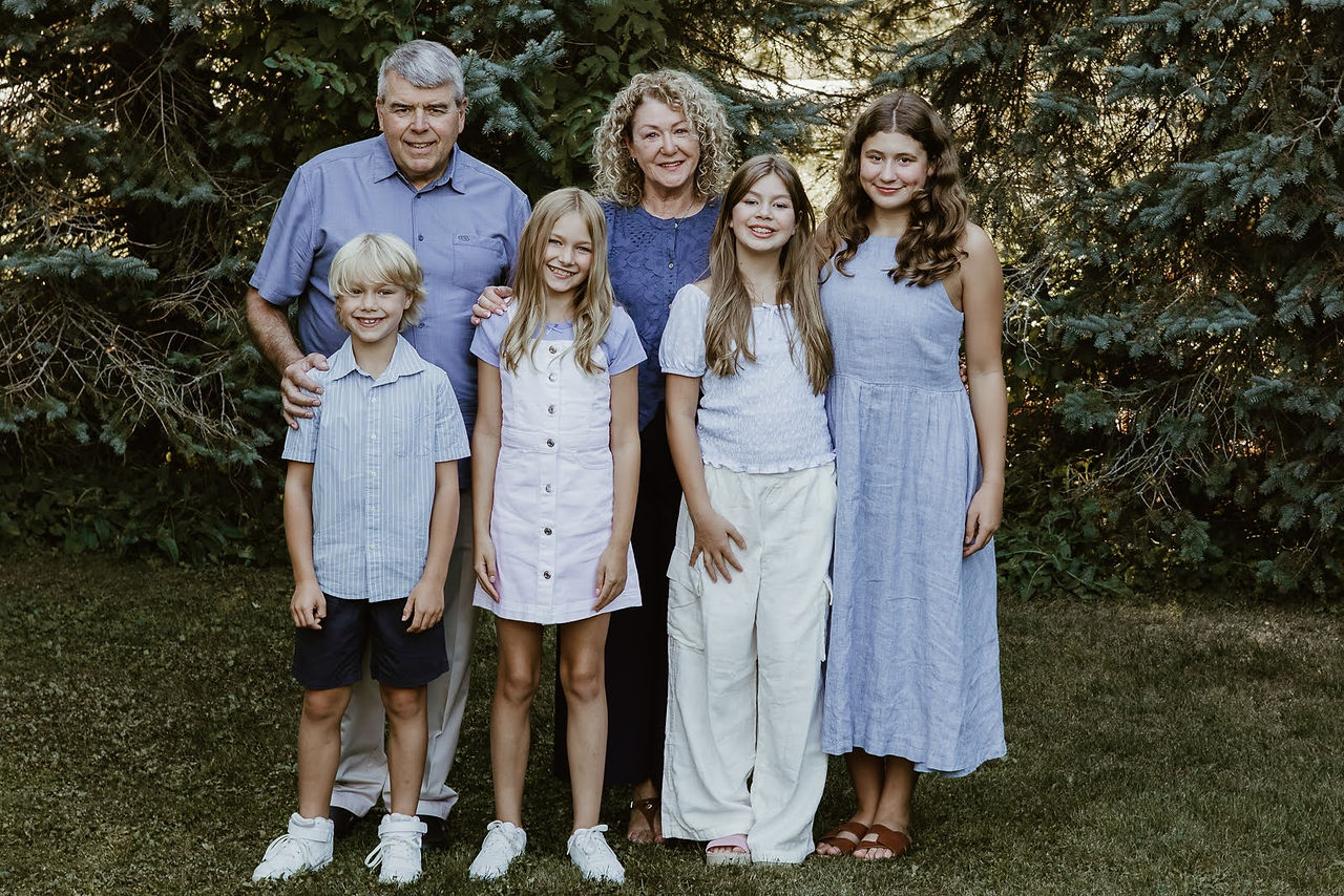 An older woman and man stand with 4 children