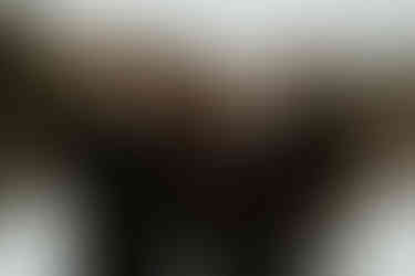 A family of five with grown children huddle together and smile outside in the snow