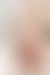 A one year old sits on the floor in front of a balloon arch and eats a small white cake