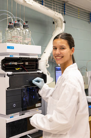 A woman in a lab coat and gloves cleans a machine