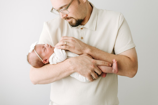 A man looks down at the newborn baby in his arms