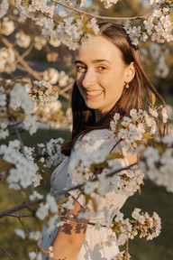 A woman stands amongst the flowering branches of a tree