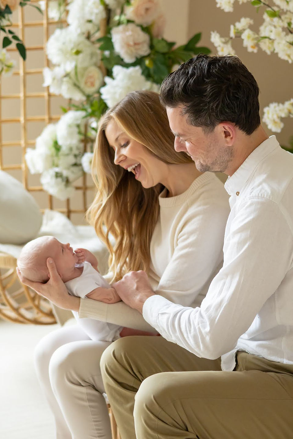 A man sits on a couch next to a woman who is holding a newborn baby