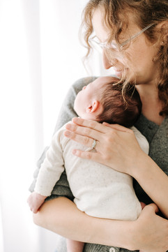 new born baby girl wearing a bow while sleeping in a Moses basket