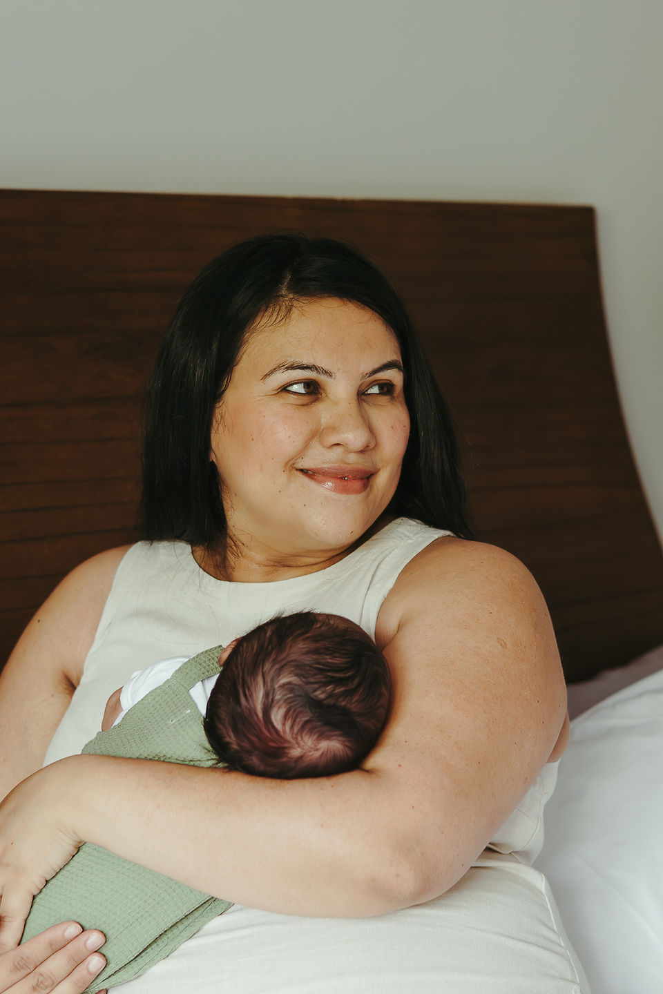 A woman holds a newborn baby in her arms and looks into the distance