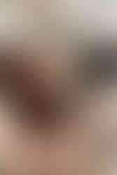 A black and white dog sits on a small wooden bench with a large floral arrangement in the background and beside the dog a woman kneels and smiles with her hand on the dog