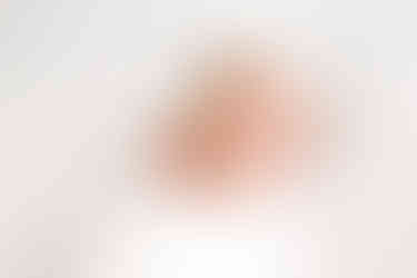 A baby wrapped in a white blanket and wearing a white hair bow