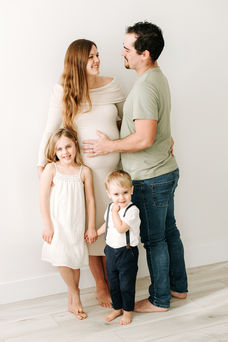 mom and dad hugging and looking at each other while son and daughter stand in front holding hands