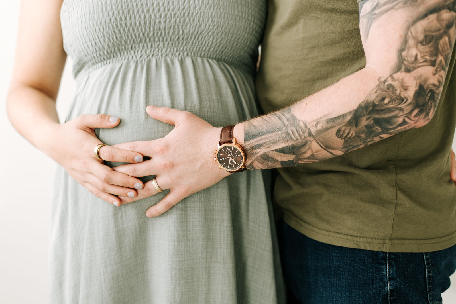 man and woman's hands rest on the woman's pregnant belly