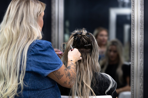 A hair dresser stands and does a client's hair