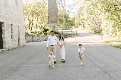A man and woman walk and hold hands as two boys run in front of them