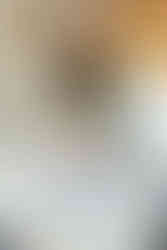 A woman in a hospital gown sits on a hospital bed and holds a newborn baby in her arms