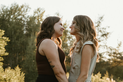 Two woman hold hands and look at each other in a field