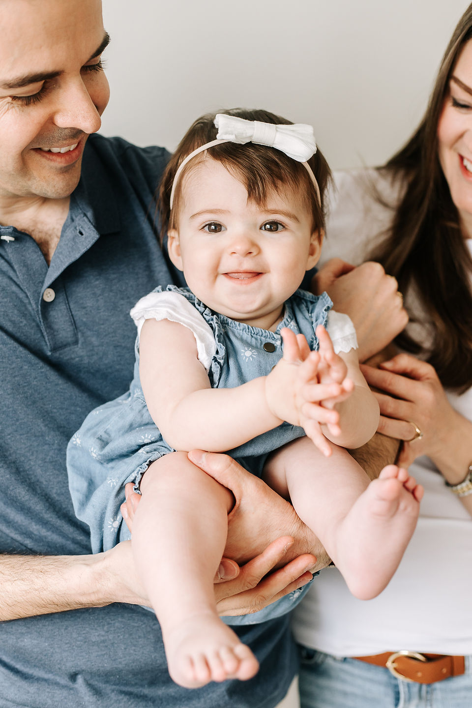 A man and woman hold a one year old girl between them