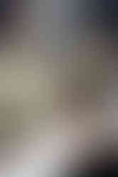 A woman sits in a hair dressers chair and looks in the mirror as she brushes her hair