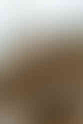 A newborn baby in a white onesie and black hair bow lies in a bassinet