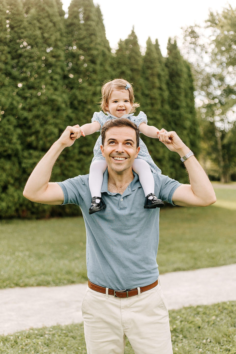 A man stands on grass with a young girl on his shoulders