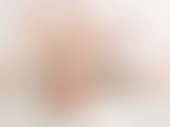 A one year old sits on the floor in front of a balloon arch and eats a small white cake