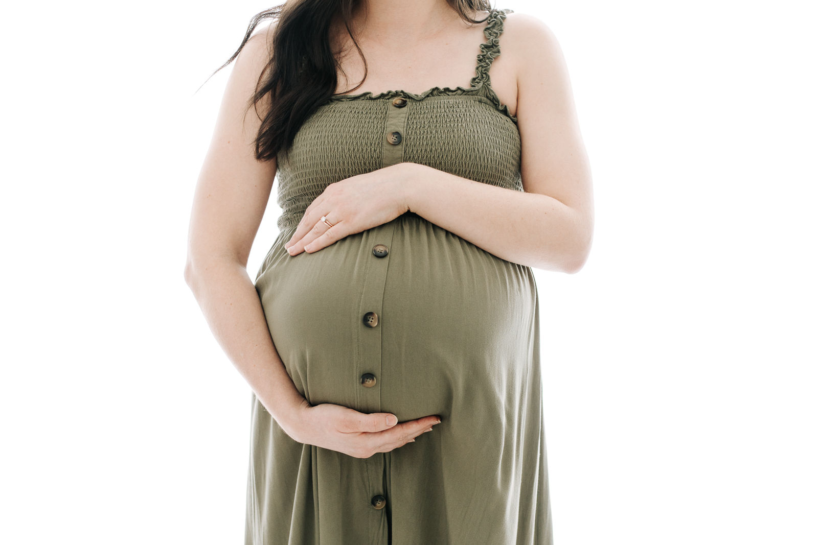 torso of a woman in a green dress cradling her pregnant stomach
