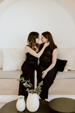 Two woman sit together as one tucks the other's hair behind her ear
