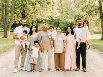 An extended family of 10 stand on a dirt path under trees