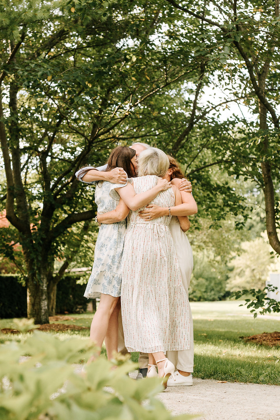 An older couple and two younger woman hug in a circle