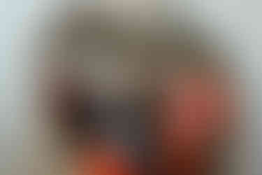 A man and woman each have a child on their lap as they smile and sit on a couch in front of a fireplace with a Christmas garland and photos on it