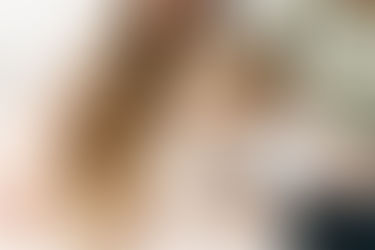 family of four sit on couch while son and daughter kiss mom's pregnant stomach