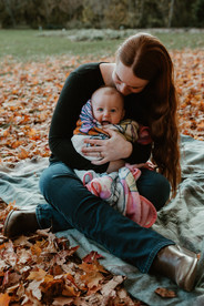 A woman looks down at the baby wrapped in a blanket on her lap