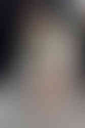 A woman sits in a hairdressers chair and smiles as she holds a pamphlet