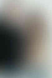 A man holds a toddler upside down as the  boy laughs and a woman kisses his cheek