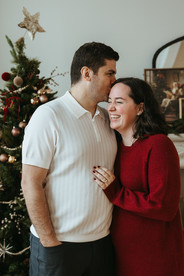 A man and woman hug in front of a Christmas tree