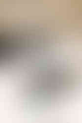 A pair of arms in a lab coat and gloves places a small dish into a scale