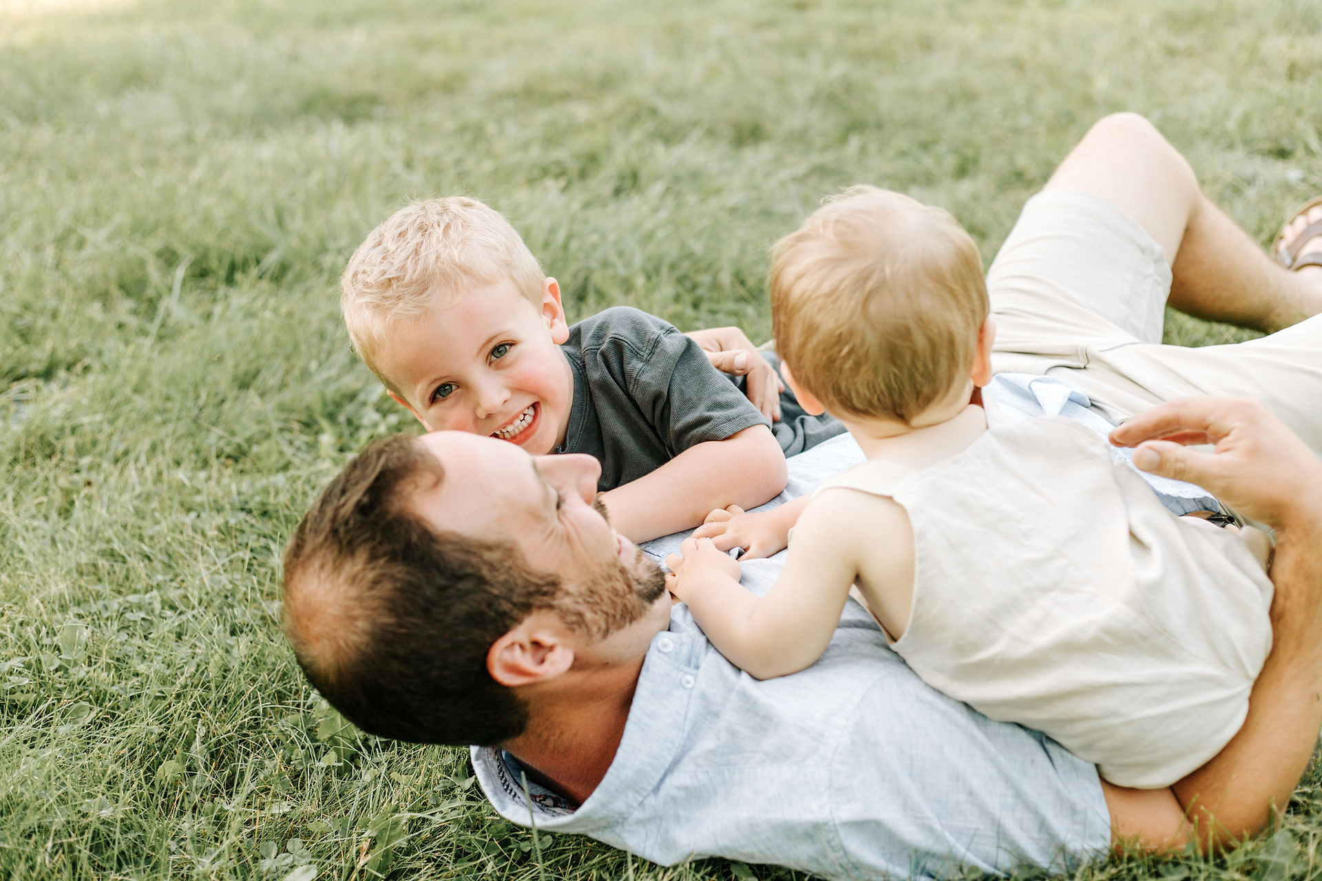 A man playing on the grass with two boys