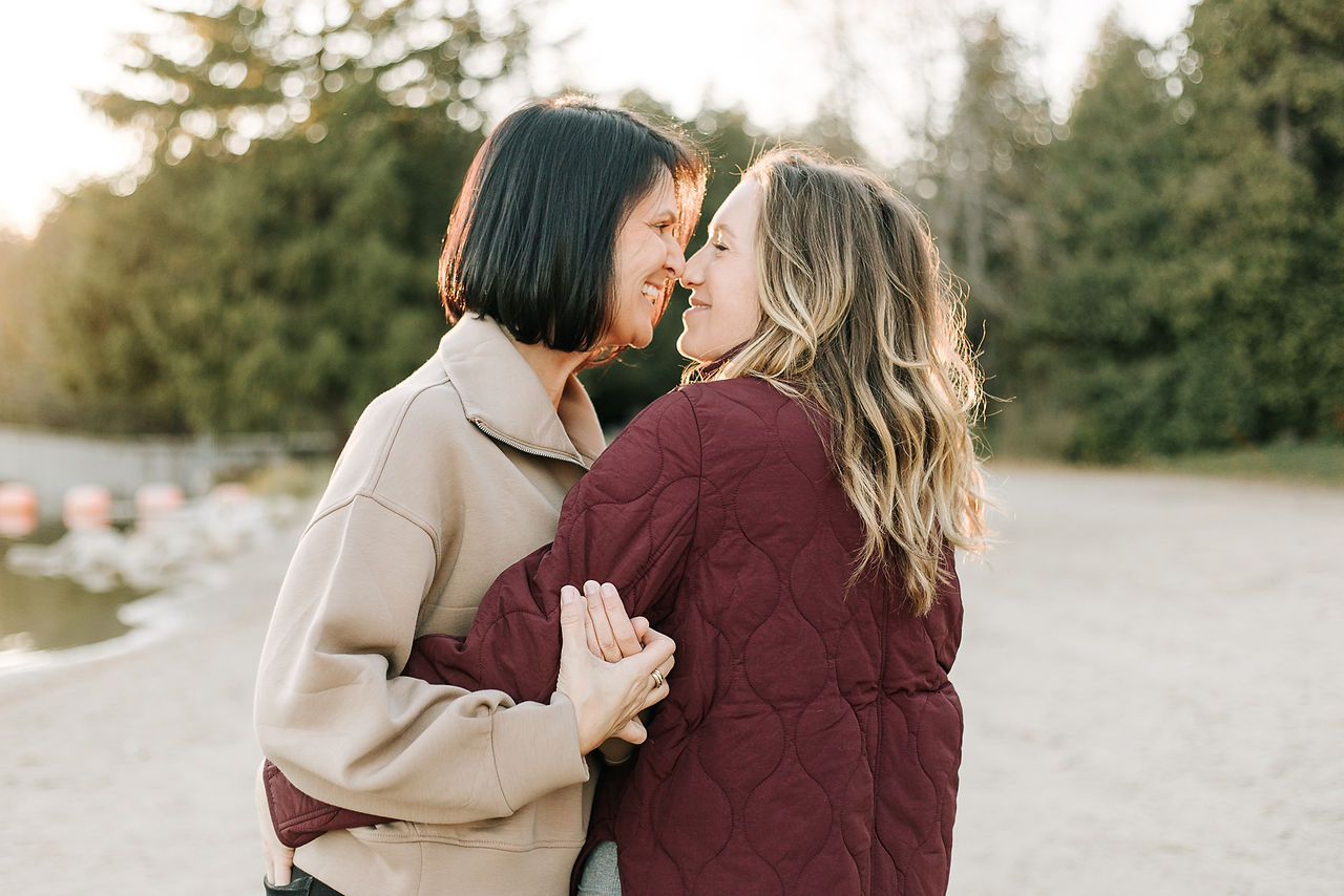 Two woman hug as the sunsets behind them