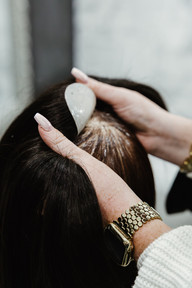 A woman stands in front of a wig and applies hair extensions to it