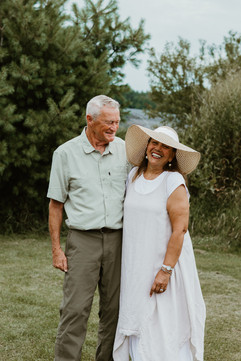 A man and woman hug as they stand in a grass field