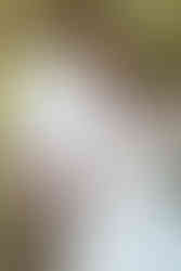 A pregnant woman and a man stand next to each other and link arms as they look into the distance