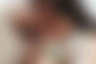 A man and woman kiss the head of a newborn baby that the woman is holding