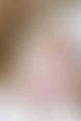 A newborn baby in a white onesie sitting on a woman's lap