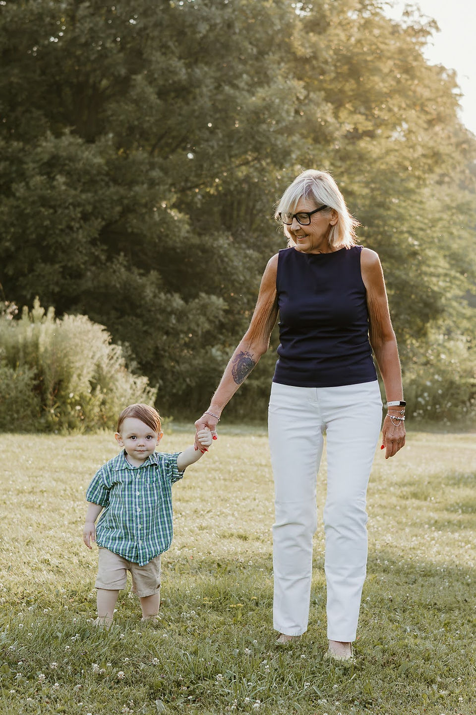 An older woman holds hands with a toddler boy