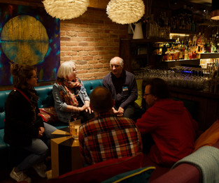 Group of people laughing and drinking cocktails in a bar